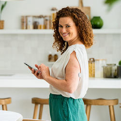 : Nasmejana ženska prenaša aplikacijo Accu-Chek SmartGuide Predict